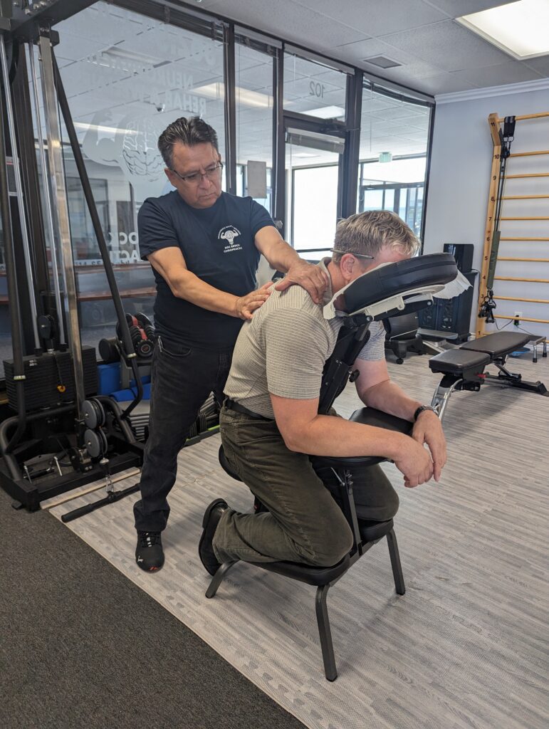 Student Massage Therapist practicing massage techniques on Dr. Brock Johnson